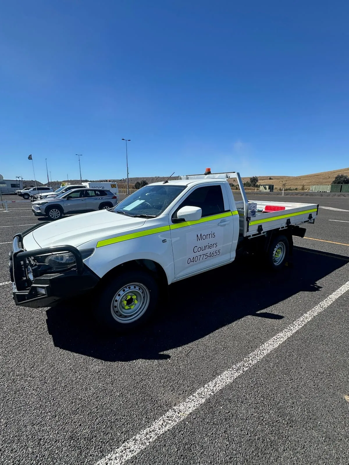 A Morris Couriers ute: white cab with a lime hi-vis stripe and an alloy tray.